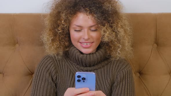 Beautiful curly woman typing message online on modern mobile phone in 4k stock video