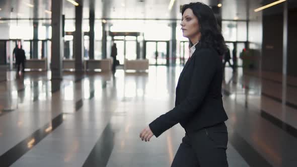 a Young Woman in a Business Suit Walks Through the Lobby of a Modern Office Building.
