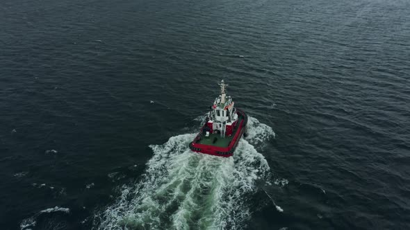 Tugboat Follows Large Container Ship Into Open Sea in Heavy Rain and Storm