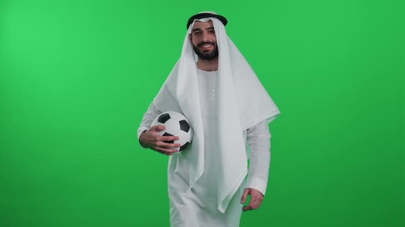 An Arab Man in a White Robe on the Background of a Chroma Key Wearing Kandura and Walks Holding a