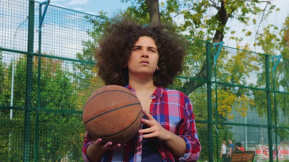 A Young Teenage Girl with an African Hairstyle Throws a Basketball Ball Into the Basket.