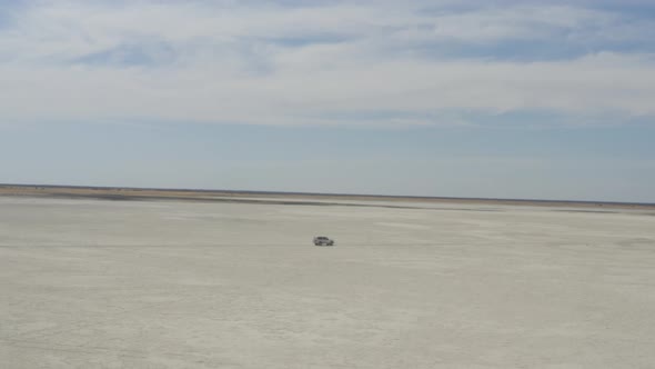 4x4 Car Driving On Vast Makgadikgadi Salt Pan At Daytime Near Kubu Island In Botswana, South Africa.