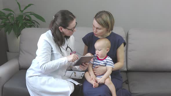 Woman Pediatrician in Uniform Glasses Showing in Tablet Child Patient Mother
