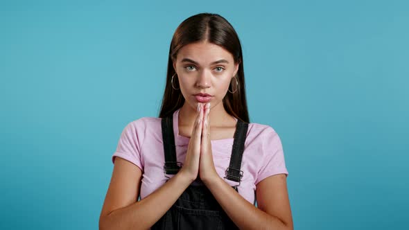 Cute Young Girl Praying Over Blue Background. Woman Begging Someone Satisfy Her Desires, Help With.