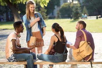 group of happy students doing homework together in park