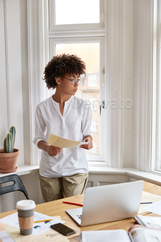 eb designer holds papers, dressed in stylish clothes, looks out of window, takes coffee break after hard work, works on new startup project.