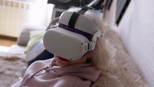 Woman Sitting on Sofa in Helmet with 3D Virtual Reality Glasses