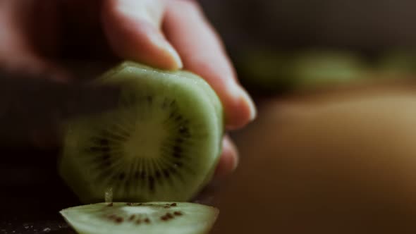 Slicing a Juicy Green Kiwi on a Black Marble Cutting Board