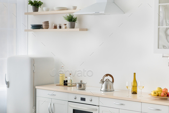 c culinary, home healthy eat. White kitchen, refrigerator, stove with kettle, plate with apples, shelves with potted plants and utensils, light wall
