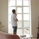 A man in a spacious room gets up from the sofa and goes to think to the big window - VideoHive Item for Sale
