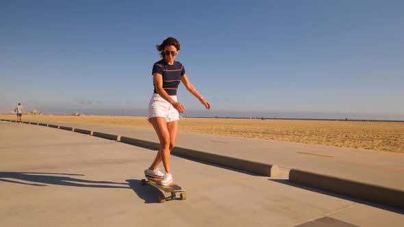 Casual Woman Longboarding On Desert Background Riding Skateboard. Wide, Slow Motion