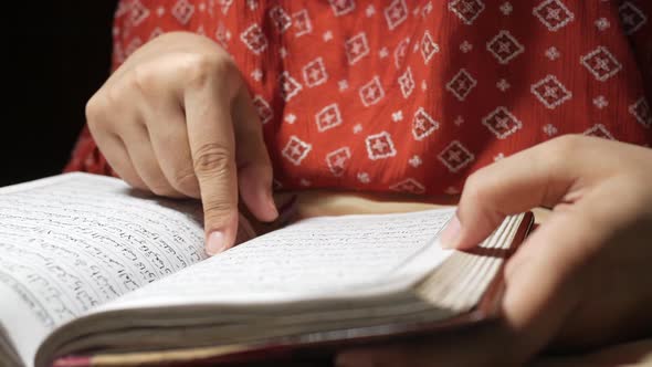 Muslim Women's Hand Reading Quran at Night alt