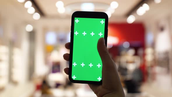 Women's Hands Press on the Screen of a Smartphone Against the Background of a Store in a Shopping