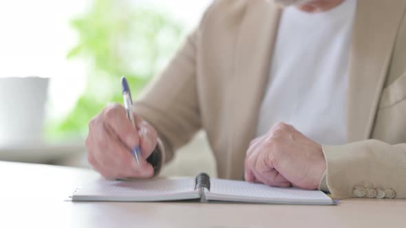 Close Up of Old Man Writing on Notebook