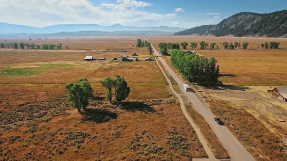 Drone takes off over the road and the endless golden steppe near Mormon Row, Wyoming, USA