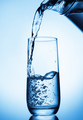 Pouring water from glass pitcher on blue background - PhotoDune Item for Sale
