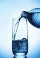 Pouring water into glass  from bottle on blue background - PhotoDune Item for Sale