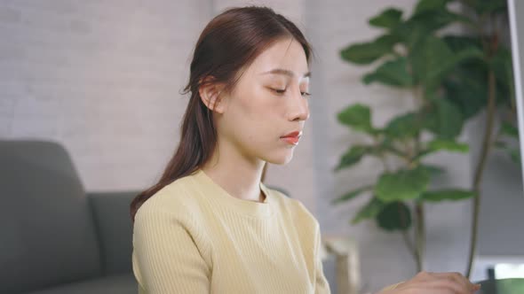 Young Asian Businesswoman Working From Home and Using Desktop Computer While Sitting in Living Room