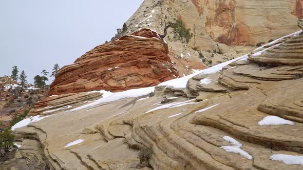 Panning red rock landscape in Zion with snow on the rock layers