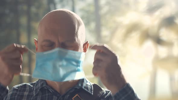 Happy man removing his face mask in nature