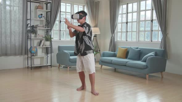 Boy Playing Video Game While Wearing VR Glasses Headset At Living Room