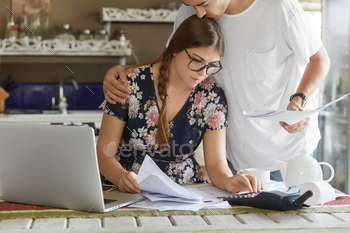 calculate interest on debt, pose against kitchen interior. Female and male read terms and conditions before signing agreement with investors