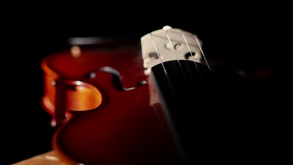 In the darkness the studio lies a violin, illuminated by beam of light, close-up. Concept of a violi