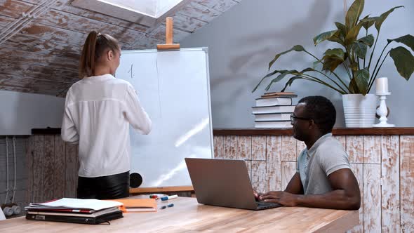 A Lesson in the Class - Woman Writting on the Board and a Black Man Sitting By the Table