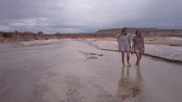 Two young women hiking upstream though desert river