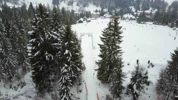 Flight Over a Ski Resort in Carpathian Mountains. Aerial View of People Descending on Skis