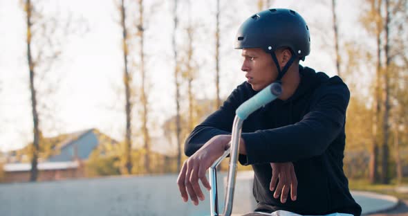 A Darkskinned Man Wearing a Helmet Standing in a Park Resting After a Bike Ride