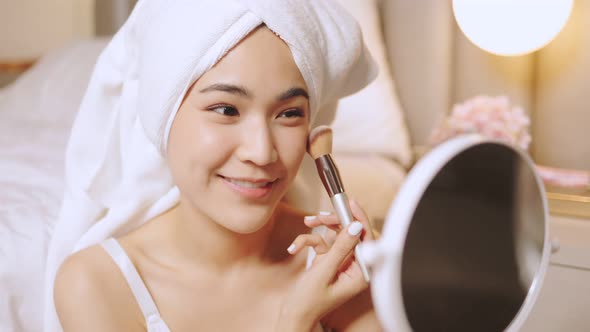 Happy attractive asian woman apply skincare cream on face and body