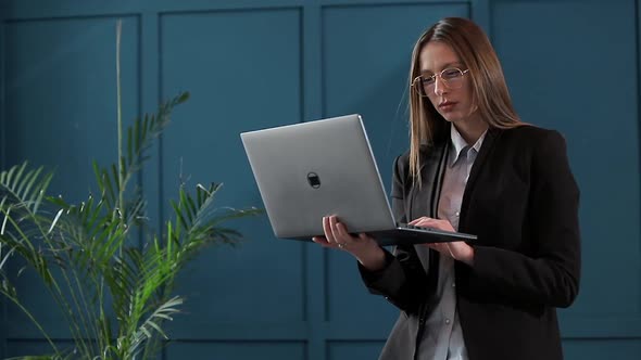 Confident Businesswoman Working on a Laptop in Her Modern Blue Modern Office Interior. Stylish