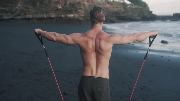 Back View of Bodybuilder with Broad Shoulders Stretching Elastic Band