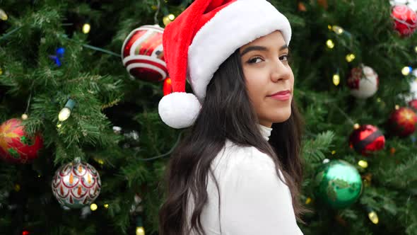 Attractive woman in a Santa hat celebrating the holiday season with a Christmas tree ornaments and l