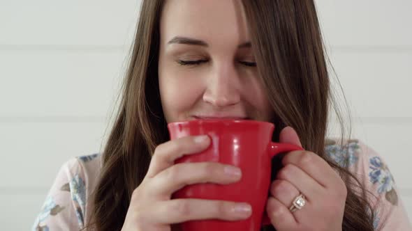 Woman smells hot cup of cocoa and smiles