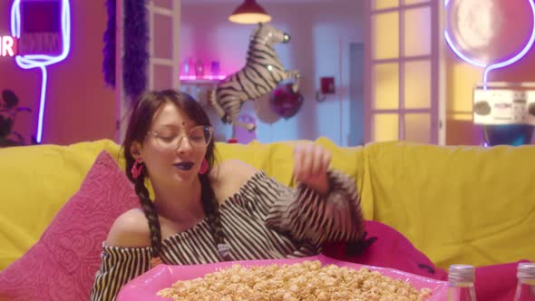 Portrait of Girl in Trendy Outfit Eating Popcorn on Sofa