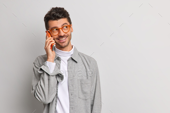 one has cheerful expression enjoys mobile tariffs and connection wears spectacles shirt isolated on grey background with copy space for your text