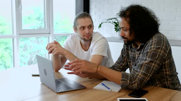 Team of two businessmen discussing new project using tablet in the office.