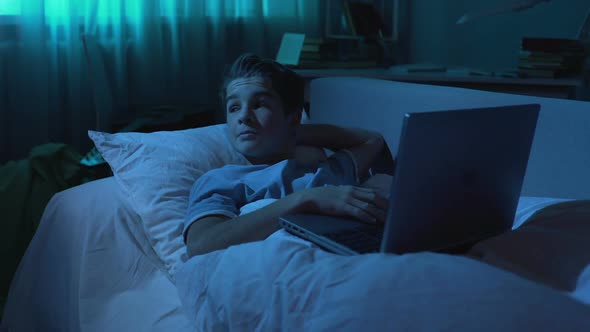 Teenager Looking Around While Chatting on Laptop in Bedroom, Playing Games