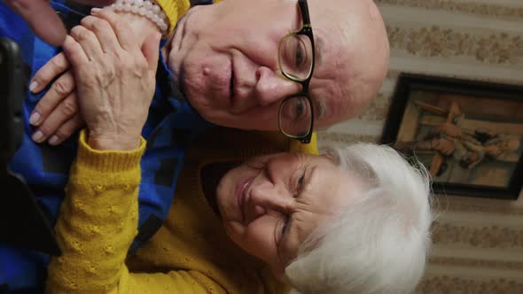 Happy Elder Lady Embracing Her Beloved Husband and Looking Into the Phone Medium Closeup Vertical