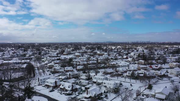 An aerial view over a suburban neighborhood in the morning, after a snowstorm the night before. The