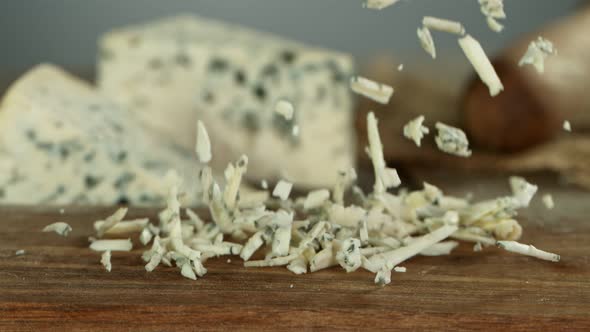 Super Slow Motion Shot of Grated Blue Cheese Falling on Wooden Board at 1000 Fps