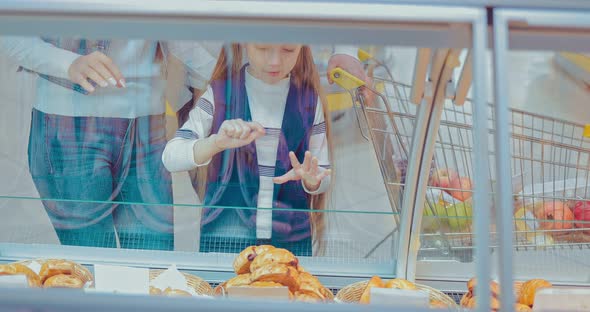 Little Girl with Family Chooses Baked Buns in the Supermarket