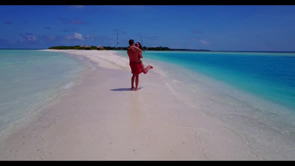 Family of two sunbathing on tranquil shore beach trip by blue sea and white sandy background of the 