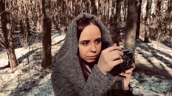 Young Woman in Gray Coat Photographing on Old Photo Camera in Forest