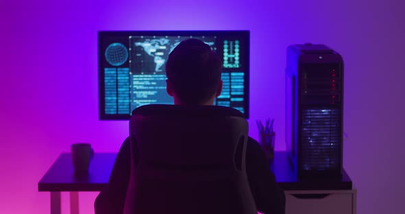 Rear View of Man Programmer Enjoying While Working at a Computer at Night