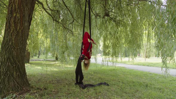 Girl Stands in Black Aerial Silk in the Park