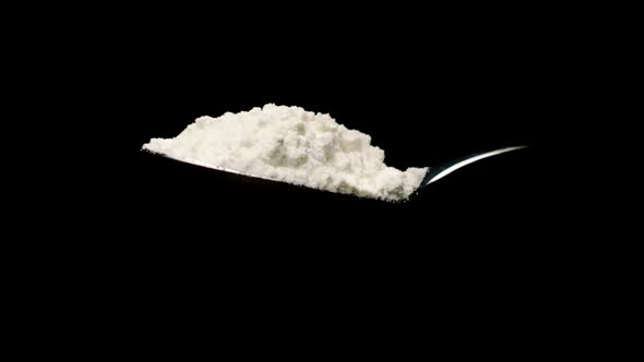 White Sugar Falling From Spoon in Slow Motion Isolated on Black Background