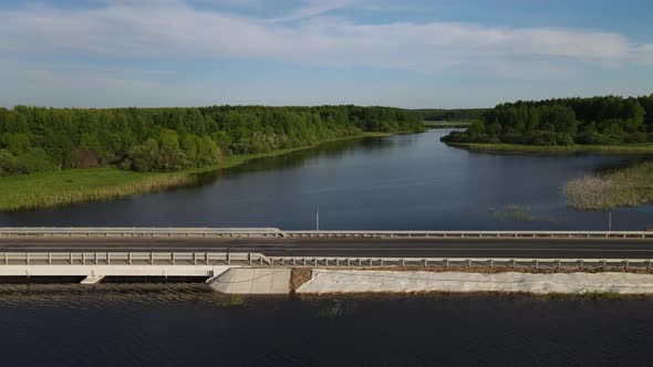 Dam Road with Vehicles Crossing Calm River